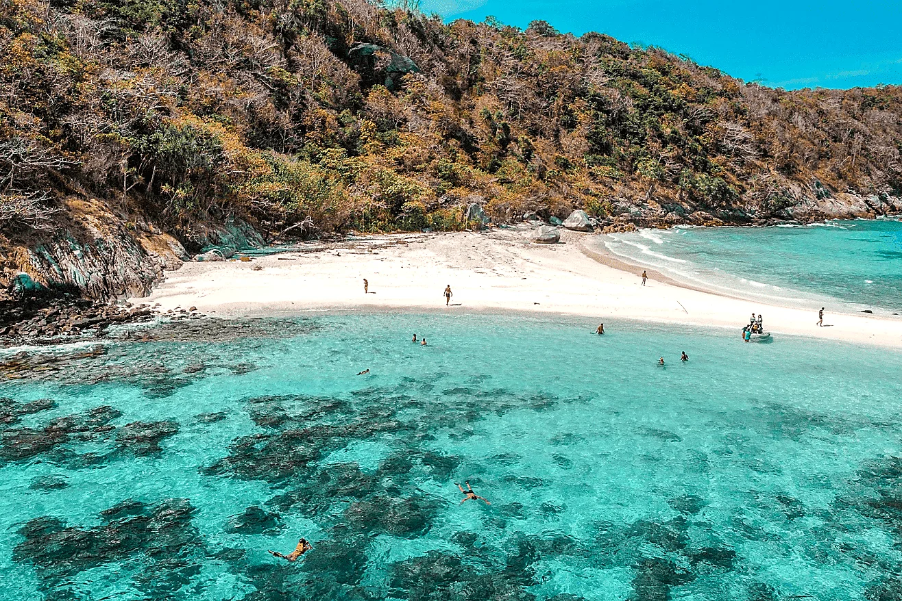White sand beach and turquoise reef with swimmers on a Phuket island
