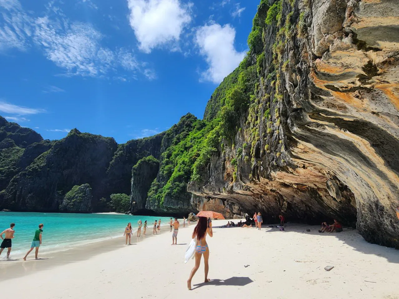 Visitors on the sand beneath the cliff at Maya Bay